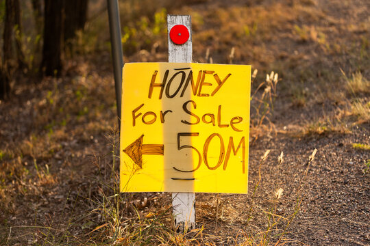 local honey for sale sign with arrow to roadside stall in Australia