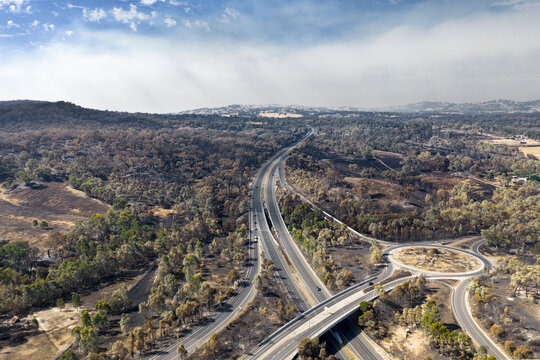 Distant bushfire smoke over burnt countryside around around winding freeways
