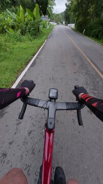 POV shot of a cyclist on a rural road, surrounded by greenery and an overcast sky, capturing the essence of outdoor adventure.