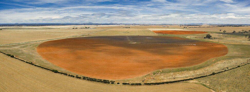 Aerial panorama view of shadows over expansive farmland and circular fields