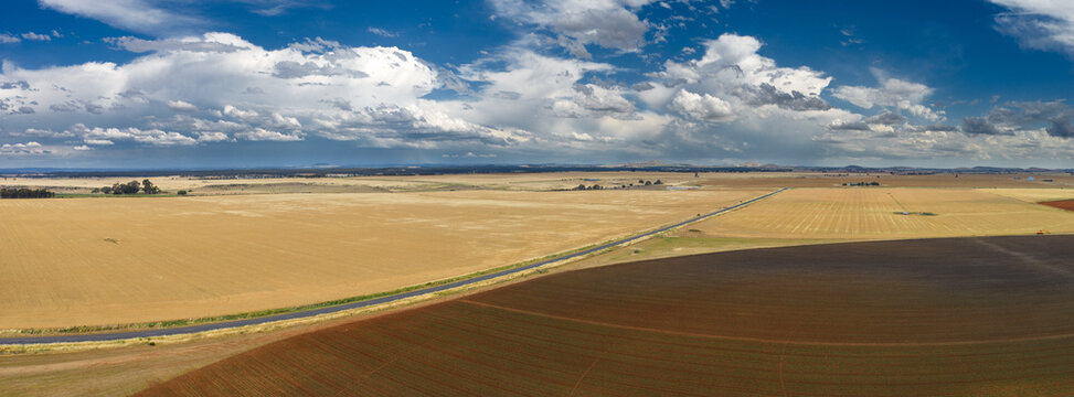 Aerial panorama view of building storm clouds over expansive farmland and circular fields