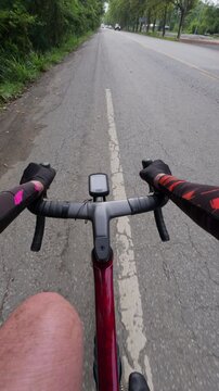 View from a cyclist's perspective on a peaceful road lined with trees, showcasing the thrill of outdoor biking.