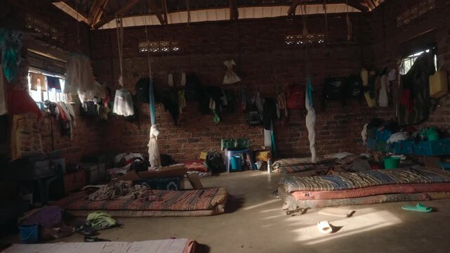 Sunlight moving across the floor of a poor, rustic orphanage with mattresses and belongings
