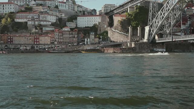 Porto Ribeira colorful waterfront with restaurants boats Dom Luis bridge base and FC Porto graffiti sign on Douro River
