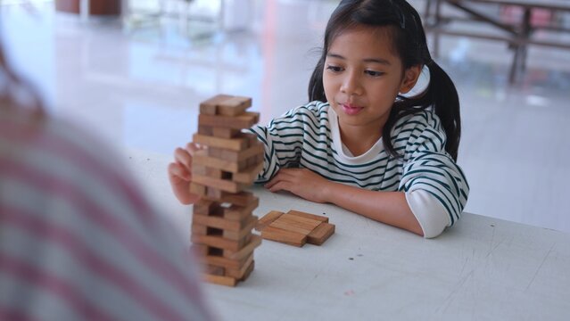 Cute Asian girl child covering eyes playfully during indoor activity to build strong mind intelligence. Witnessing authentic raw emotion adds incredible value to media. Top tier educational media.
