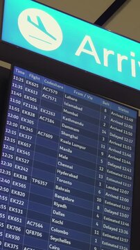 Digital arrival flight status boards at Dubai International Airport, UAE.