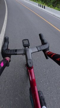 A cyclist's view on a winding road, showcasing the thrill of outdoor biking amidst lush greenery and smooth asphalt.