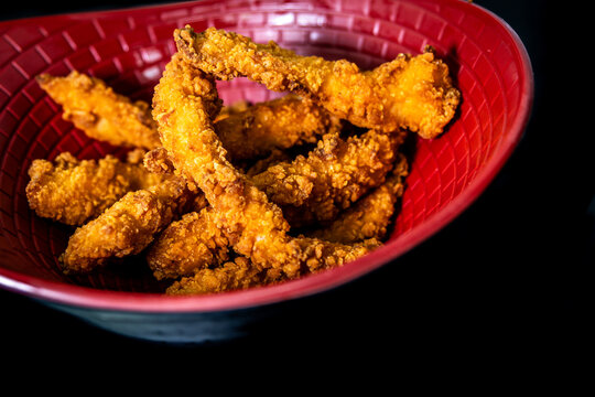 Crispy golden fried chicken strips served in a red bowl, a popular fast food snack