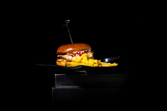 Gourmet burger with french fries on a dark background, representing delicious fast food