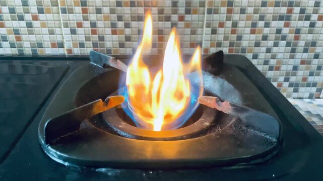 Orange and blue flames burning on gas stove burner, vibrant fire colors creating a dynamic cooking and kitchen energy concept.