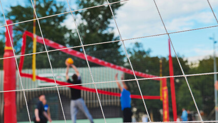 Volleyball players competing during sports day, seen through net