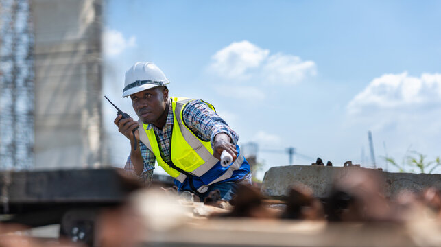 Railway construction supervisor using walkie talkie to coordinate rail installation, Industrial engineer inspecting railway tracks and giving instructions via radio at a construction site