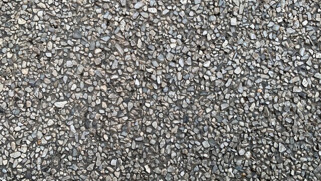 Close-up of exposed aggregate concrete surface showing small stones embedded in cement, forming a durable textured pavement