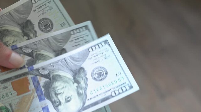 Close-up of rough hands counting paper dollars. Cash.