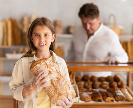 Girl in bakery chooses bread, considers various product options.