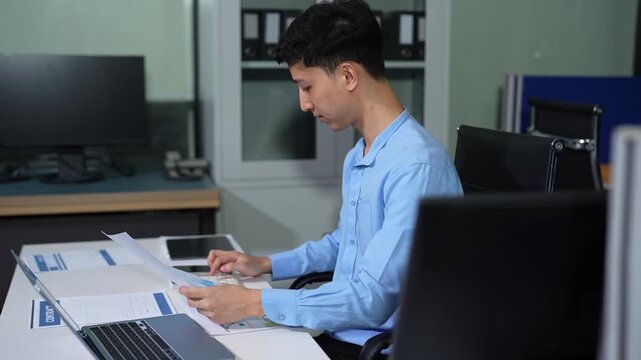 Young employee using computer working online, doing searching, taking notes, watching business training webinar in office, having virtual chat meeting looking at laptop at work.