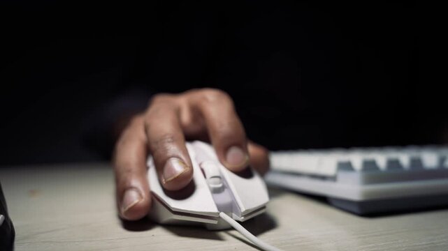 Close-up hand clicking computer mouse with keyboard background