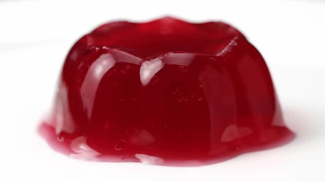 Vibrant red gelatin dessert (jelly or jello) in a molded shape, photographed close-up against a clean white background