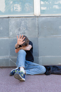 Lonely teenager showing a stop sign sitting on the floor