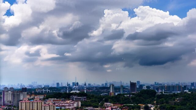 Dramatic morning to afternoon time lapse over a modern urban skyline with moving clouds and sun rays in Shah Alam, Malaysia.