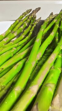 Bright green asparagus spears simmering in boiling water capturing the vivid color and texture of the blanching process, Dolly In