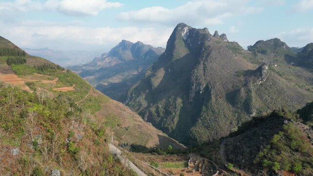 Aerial drone shot of towering limestone peaks rising above rugged mountain valley near Dong Van, showcasing striking karst terrain and scenic landscape in Ha Giang, Vietnam