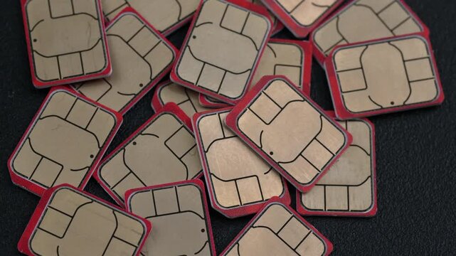 A collection of SIM cards scattered across a dark surface. Useful for tech presentations or mobile communication topics.
