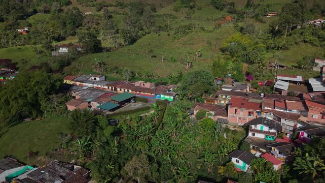 Aerial view of colorful village houses surrounded by lush green hills and farmland