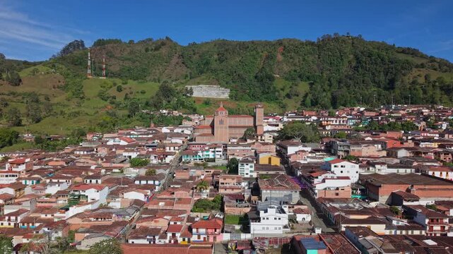 Aerial view of Jerico town with colorful buildings and central church, lush hills behind