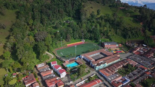 Aerial view of Jerico sports complex and colorful buildings beside lush green hills