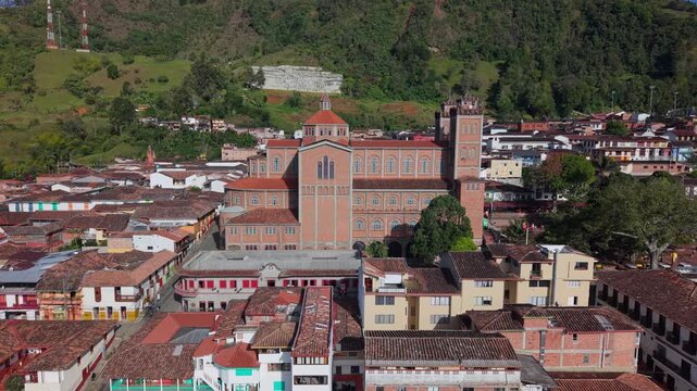Aerial view pulls back from red-brick cathedral over Jericos main plaza and rooftops