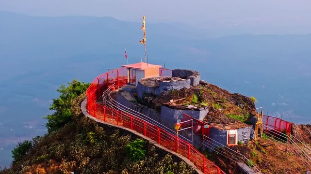 Small Temple on Hill top with religion flag, haze and mountains at Baba Budangiri, Chikkamagaluru, karnataka, india. day time, semi orbit shot, drone shot, 4k.