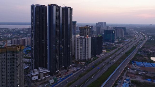 glass faded buildings with tower buildings, Nehru Outer Ring Road and vehicles at financial district, Nanakramguda, gachibowli, hyderabad, telangana, india. sun set time, zoom in shot, drone shot, 4k.