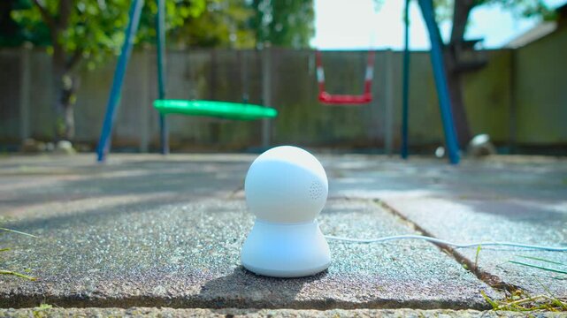 Smart playground monitoring camera for child safety in backyard garden. AI outdoor surveillance device supporting remote supervision near children swings and family recreation area. Connected home