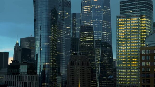 A cinematic close-up drone shot jibbing upward alongside New York City's iconic skyscrapers. The camera rises smoothly past towering glass and steel facades, revealing the immense scale and architectu