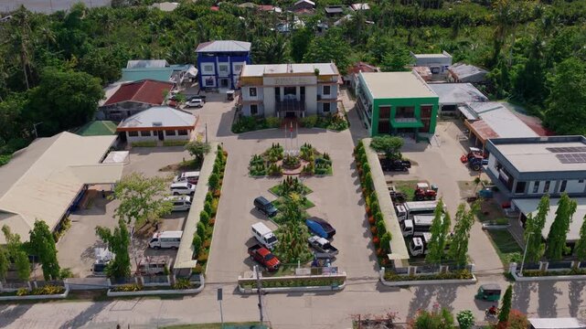 Symmetrical aerial pullback of Inabanga Municipal Hall grounds and parking area, drone, Bohol Philippines