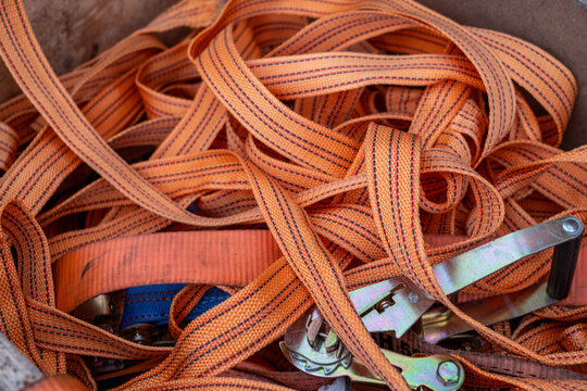 Orange ratchet straps in a tangle, ready for cargo securing and industrial transport