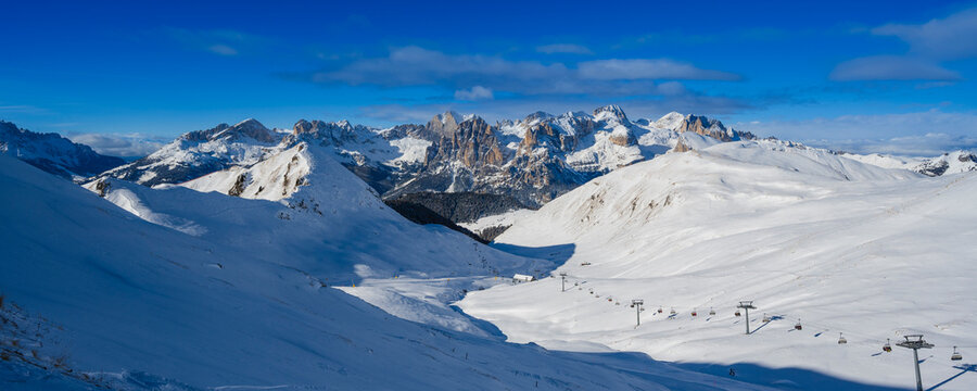 Snow-covered mountain range with ski lifts under a clear blue sky.