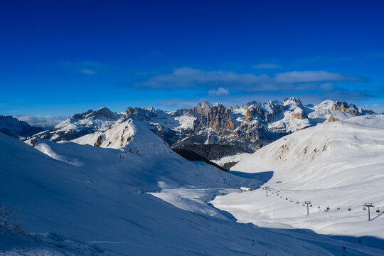 Snow-covered mountains under a clear blue sky with ski slopes and distant peaks.