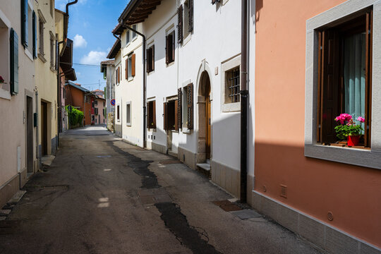 Narrow street with colorful houses, shuttered windows, and sunny sky.
