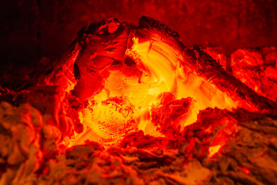 Glowing embers with intense heat and vibrant red-orange hues in a dark setting.