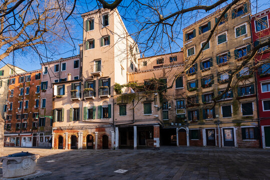 Picturesque Italian street with colorful buildings under a clear blue sky and bare trees.