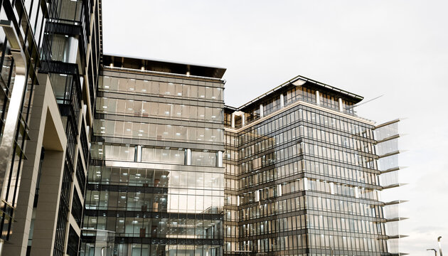 Modern glass office building under a cloudy sky in an urban setting. Illustration, rendering