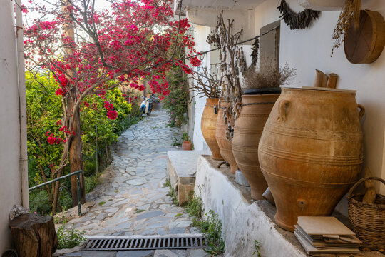 A picturesque, narrow alleyway in the traditional village of Spili, Crete, Greece. Traditional large clay jars (pithoi) outside a residence, enhancing the authentic charm and rustic rural atmosphere