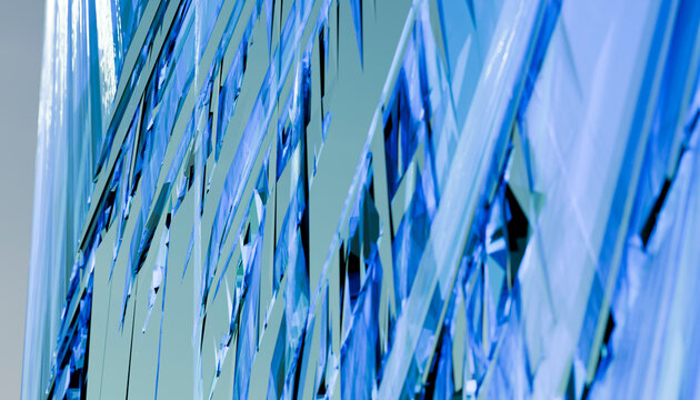 Abstract close-up of angular blue-tinted glass windows reflecting light.
