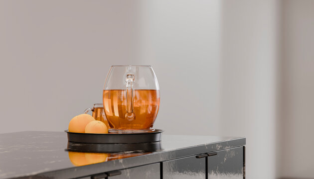 Glass teapot with warm tea and lemons on a black tray in a modern kitchen setting.
