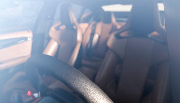 Interior of a luxury car showing leather seats and a steering wheel in soft focus.