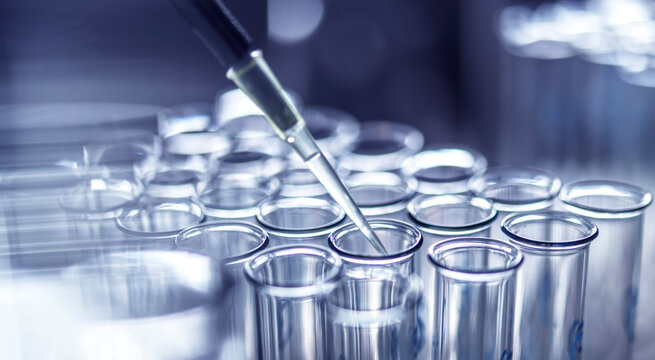 Laboratory test tubes with a pipette for scientific research in a blue-toned setting.  