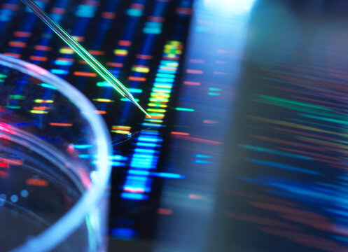 Close-up of colorful DNA sequencing data on a screen with a laboratory pipette.