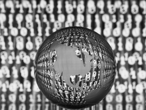 Transparent globe with binary code projected on its surface, in a digital black and white theme.